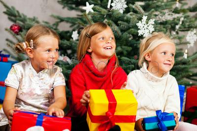 Family Christmas - three children having received gifts showing them around