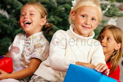 Family Christmas - three children having received gifts showing them around