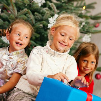 Family Christmas - three children having received gifts showing them around
