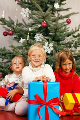 Family Christmas - three children having received gifts showing them around