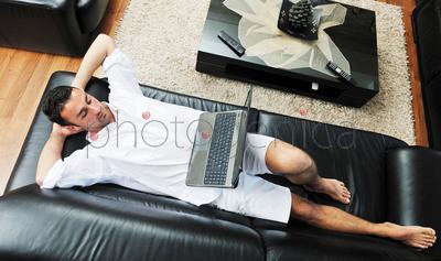 Portrait of a relaxed young guy using laptop at home indoor